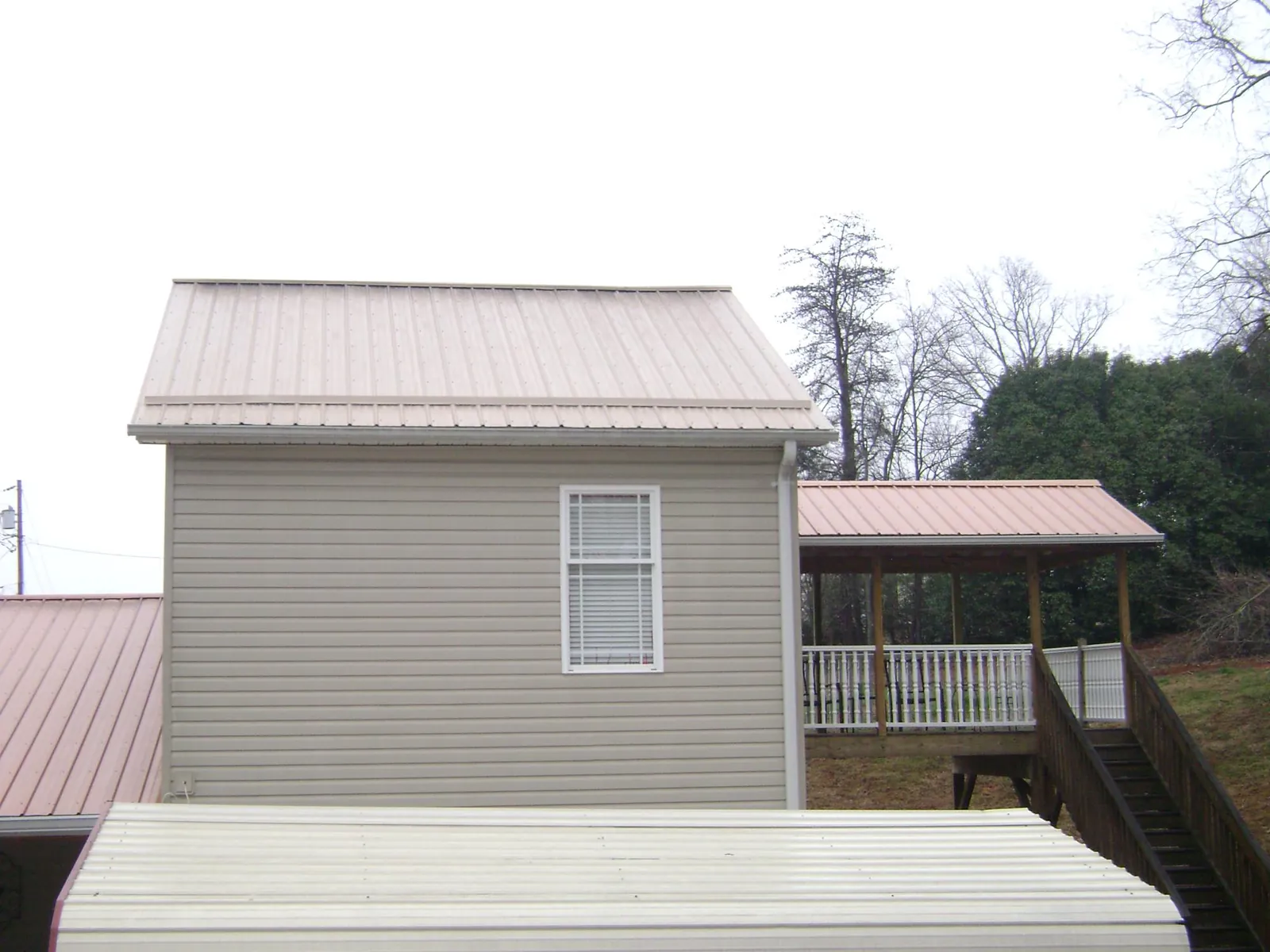 Tan metal roofs on a two story addition and attached porch, from a Roof Replacement job in Aberdeen