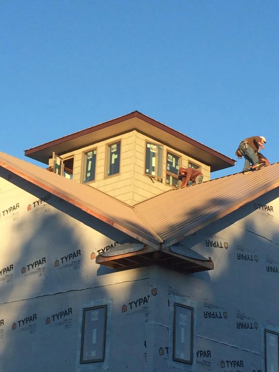 Roofers working around a rooftop cupola on a new metal roof at sunset — Roof Waterproofing in Aberdeen by Roofing Brothers